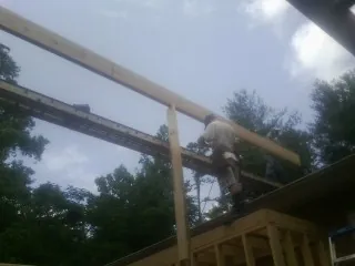 Carpenter setting a ridge beam over a new addition frame — Ice Dam Removal by Roofing Brothers in Marine City