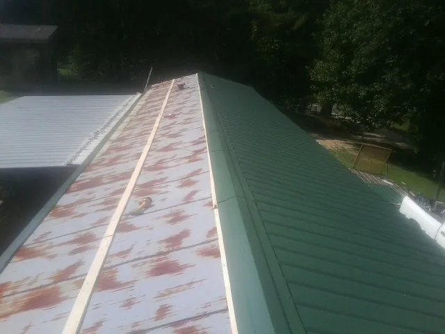 Old rusted panels beside newly installed green metal roofing — Wind Damage Roof Repair by Roofing Brothers in Marine City