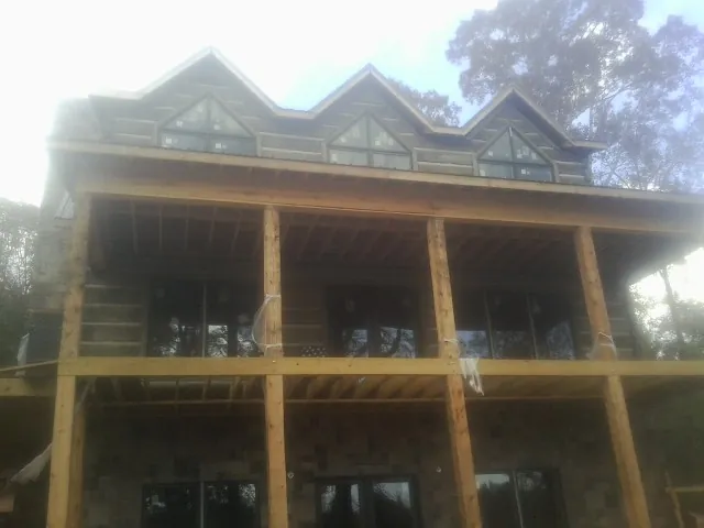 Dormers and porch framing on a large log home under construction — Roof Coating work by our crew in Marine City