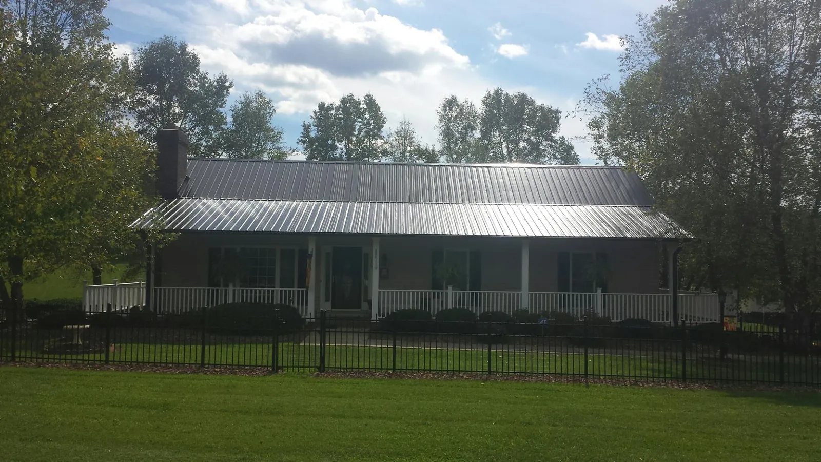 Gray metal roof on a brick ranch with a full width front porch — Gutter Guard Installation work by our crew in Marine City