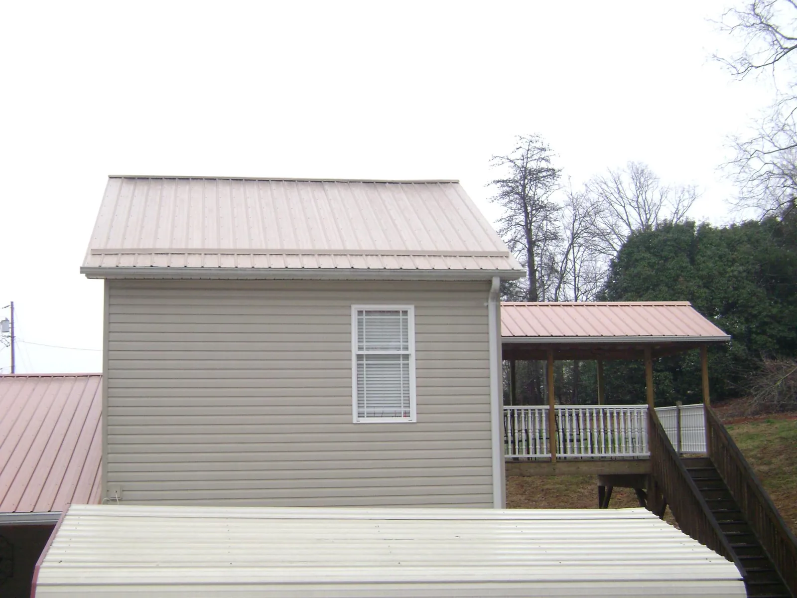 Tan metal roofs on a two story addition and attached porch, from a Roof Replacement job in Marine City
