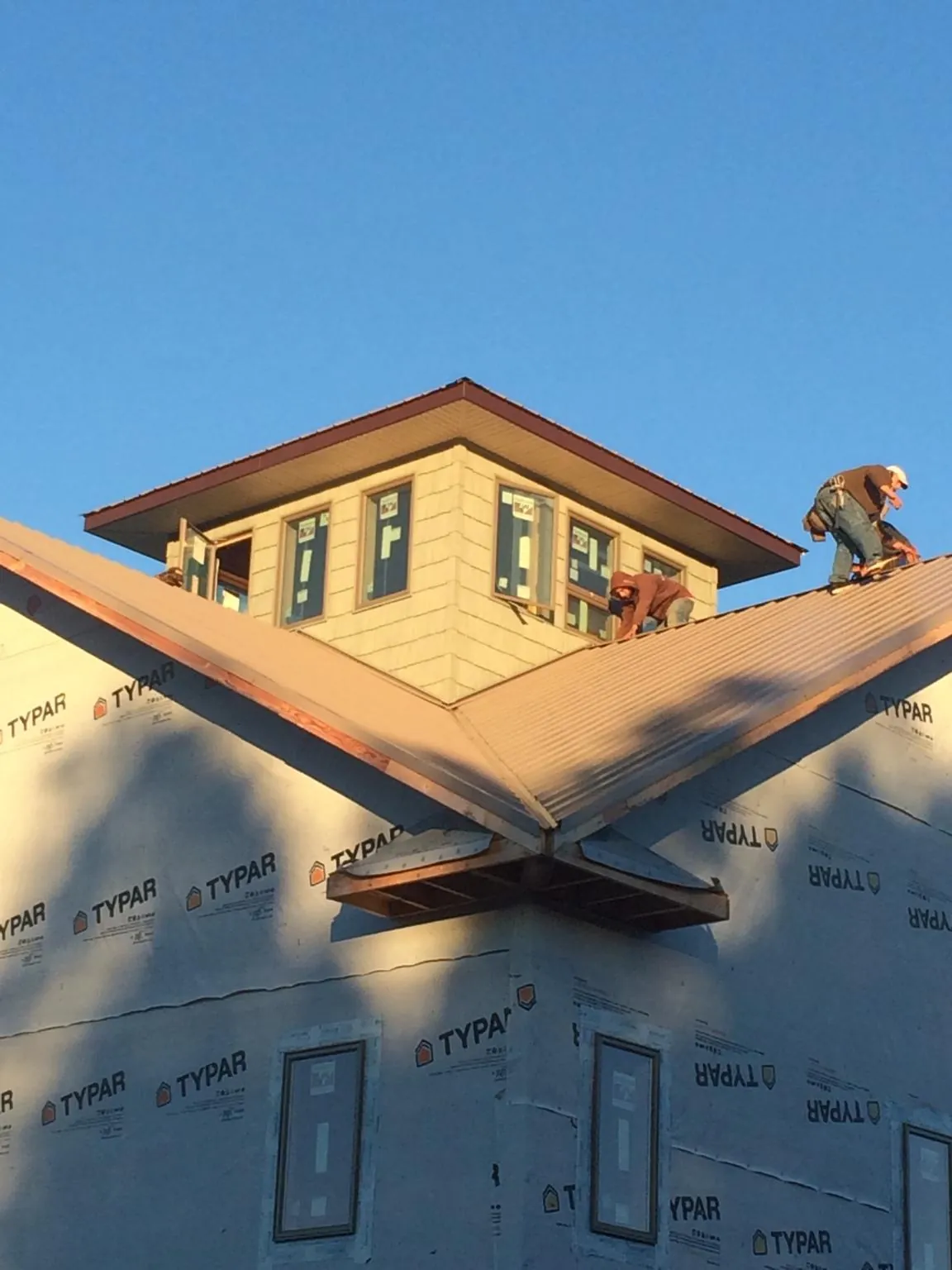 Roofers working around a rooftop cupola on a new metal roof at sunset — Roof Waterproofing in Marine City by Roofing Brothers